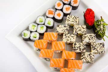 Japanese Cuisine - Appetizing Salmon Sushi Set. Philadelphia Sushi Roll - Maki Sushi with Philadelphia Cheese inside on mirror black background. Smoked salmon rolls served on a plate