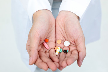 Asian doctor holding medicine capsule tablets pills on palm of hand
