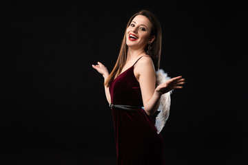 smiling woman in dress with wings looking at camera isolated on black