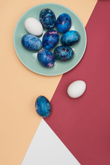  Happy Easter. Easter festive eggs in a blue plate on a colorful background. Top view.
