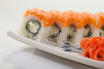 Japanese Cuisine - Appetizing Salmon Sushi Set. Philadelphia Sushi Roll - Maki Sushi with Philadelphia Cheese inside on mirror black background. Smoked salmon rolls served on a plate