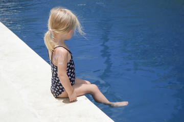 Adorable blonde toddler girl enjoying day at the pool. Summer vacation concept.