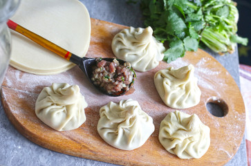 georgian dumplings khinkali with cilantro, coriander on kitchen board close up photo with human hand