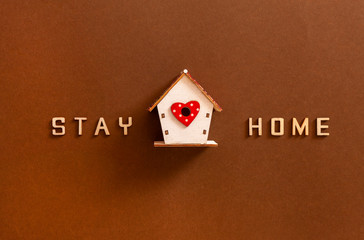 Words Stay home made from wooden letters and wooden figures of house, concept of self quarantine at home as preventative measure against  corona virus Covid19 outbreak. Staying at home during pandemic