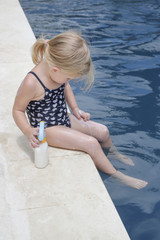 Cute little toddler girl applying sunscreen protection cream. Sun blocking lotion for protecting baby from sun during summer vacation. Children healthcare and skin care during travel time.