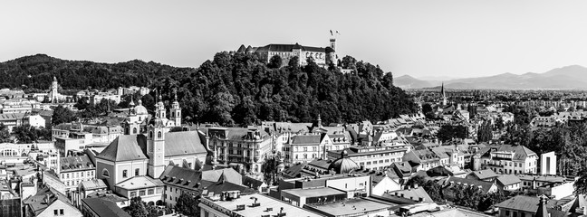 Old town and the medieval Ljubljana castle on top of a forest hill in Ljubljana, Slovenia in black and white