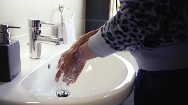African American woman washing hands in faucet