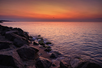 Sunrise at sea. Stones, waves and the sun. Seascape.