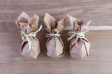 Festive set of Easter eggs wrapped in organic craft paper on a rustic wooden background. Festive table decor. Close-up