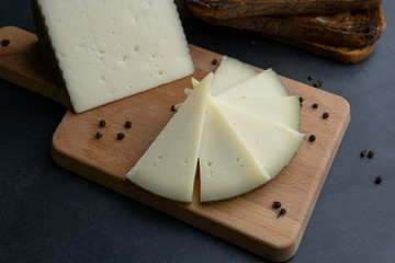 Queso curado Manchego espa&ntilde;ol sobre una tabla de cortar