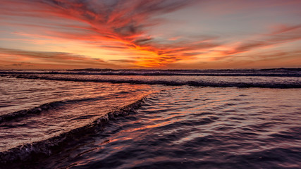 mar con cielo rojizo y nubes de atardecer con olas