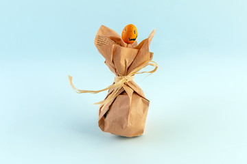 Handmade Easter egg in brown kraft paper on a blue background. Conceptual image of green consumption.