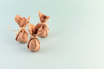 Eco-friendly Easter gift - a set of eggs wrapped in kraft paper on a blue background. The concept of eco-friendly and reasonable consumption of gifts. Copy space.