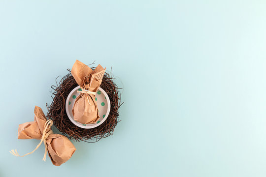Easter table decor: a set of eggs wrapped in eco-friendly packaging in a nest of dry branches. Copy space