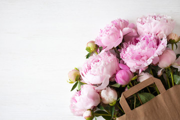 Bouquet of pink peonies in a paper bag on the table