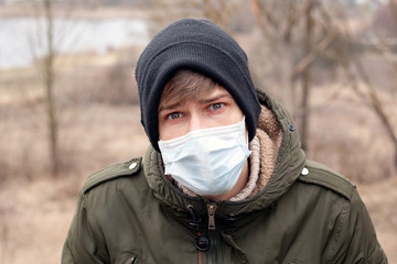 Fototapeta na wymiar young man in medical disposable mask stands on the street. respiratory viral disease pandemic coronavirus flu quarantine covid-19