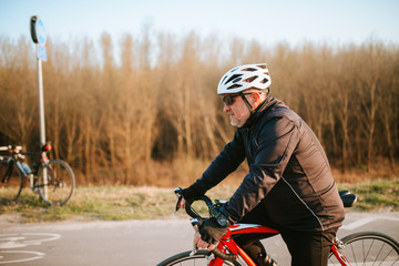 Naklejka premium A senior cyclist rides a bicycle on the road