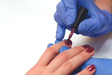 manicure specialist covers the nails with red varnish, toned.