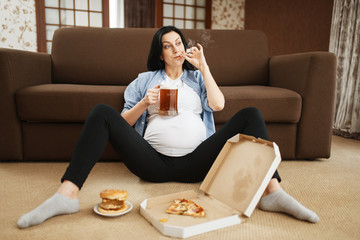 Pregnant woman with belly smoking and drinks beer