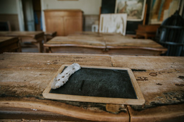 Vintage slake chalkboard on old school-desk with rabbit leg used to erase the writing.