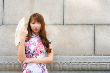 Portrait of Chinese girl wearing Chinese clothes holding paper folding fan in her hand