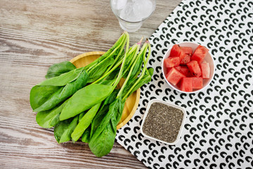 Top view of a table with spinach, chia seeds, watermelon and ice. Ingredients for a tasty and healthy smoothie.
