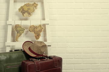 travel old suitcases, cowboy hat and world map on brick wall background                       