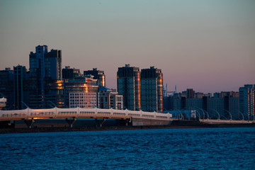 Fototapeta na wymiar modern city buildings and expressway by the sea in the evening in the light of the setting sun
