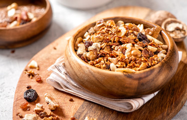 Homemade toasted granola with oats, honey, walnuts, raisins, flax and sesame seeds in a wooden bowl...
