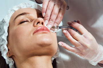 lip shape correction procedure in a cosmetology salon. The specialist makes an injection on the...