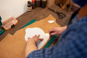 The master works with genuine leather in his workshop. Handmade leather goods manufacturing. Working with genuine leather.
