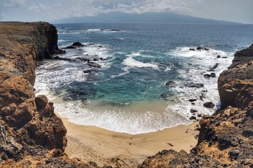Fototapeta na wymiar White foamy waves wash assure on a bay on the islet of Djeu in Cabo Verde