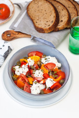 Salad bowl with chopped tomatoes, pepper, cream cheese, black sesame and pumpkin seeds