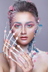 Beautiful girl in the image of a sweet fairy with art make-up and with long design nails. Creative manicure.