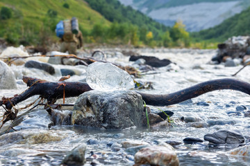 Pieces of ice on a mountain river in Svaneti, Georgia, a person crosses a mountain cold river