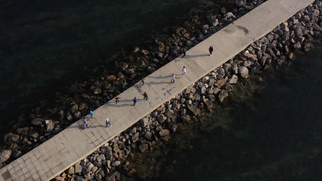 Above top view children training outdoors aerial 4K. Children play sports on the pier by the sea. They run and jump under the guidance of a coach.