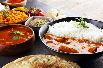 Chicken tikka masala spicy curry meat food in pot with rice and naan bread. indian food on table