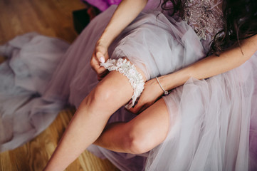 Obraz na płótnie Canvas bride in a wedding dress puts on a garter