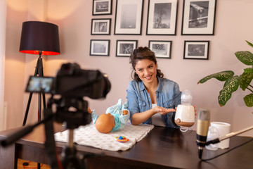 Female vlogger making tutorial about baby bottle milk heating