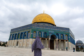 A muslim woman comes to pray on the Temple Mount with the golden Dome of the Rock in front of her