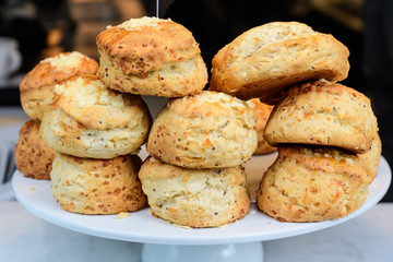 Freshly baked homemade English scones with dried fruits, displayed as a pyramid, available for sale at a café in London, side view of healthy food photographed with soft focus