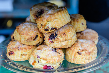Freshly baked homemade English scones with dried fruits, displayed as a pyramid, available for sale at a café in London, side view of healthy food photographed with soft focus