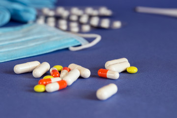 Medical multi-colored pills on a blue background. Treatment of viruses and diseases.