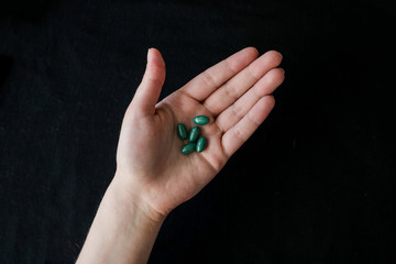 Bright green pills in a hand, isolated on a black background