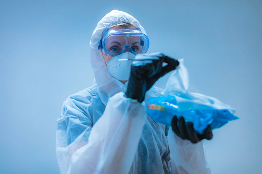 Medical Doctor, Scientist In Full Body Suit For Prevention From Viruses And Diseases Holding A Antiseptic Tissue For Disinfection.