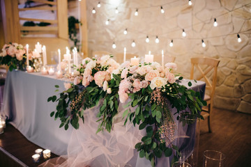 Romantic wedding table of newlyweds decorated with a blue tablecloth, candles, flowers in the style of rustic