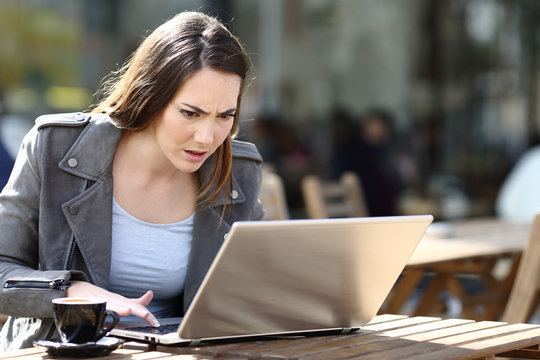 Angry woman pressing button on laptop in a coffee shop