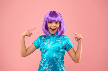 I love my new hair. Little girl pointing at violet hair. Happy child wear fancy hair wig. Haircut and hair color. Beauty salon. Beauty and fashion