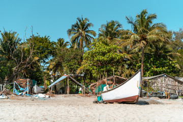 Naklejka na ściany i meble Fishing boat on the beach against the background of palm trees