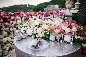 Table decorated for date for two, there are tableware, glasses, flowers, candles and tablecloth with napkins, the table is on a balcony